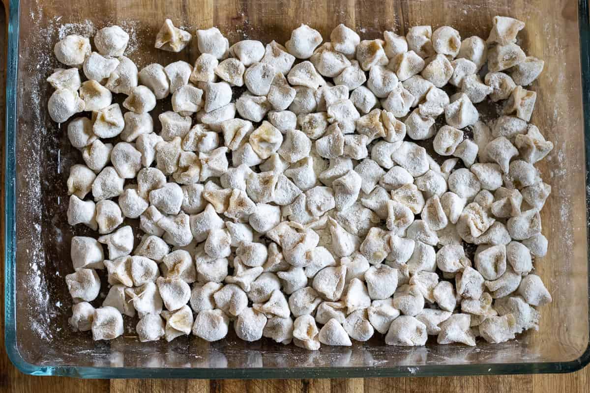 small Manti dumplings are placed on a floured tray