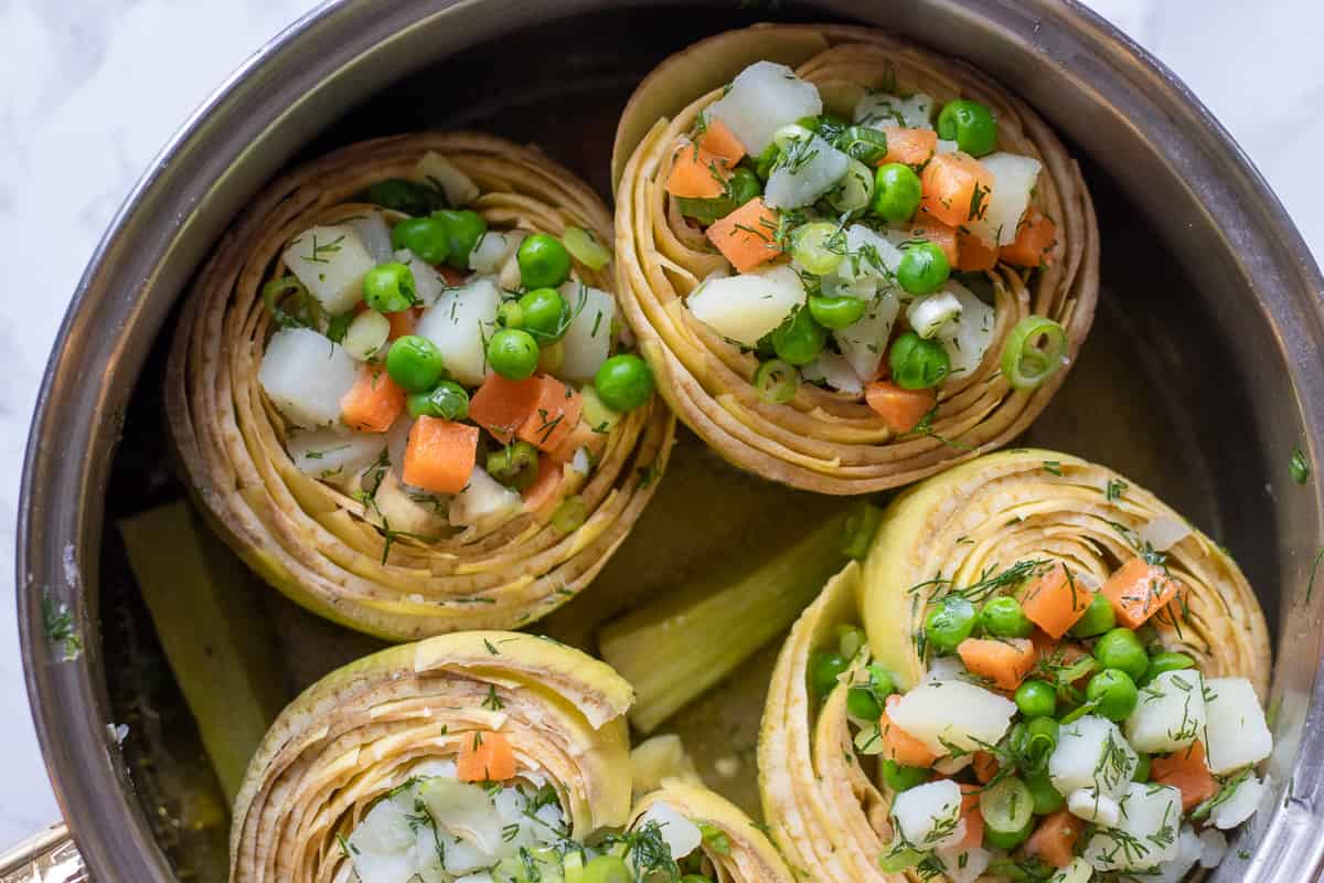 artichokes are filled with stuffing and placed in a saucepan