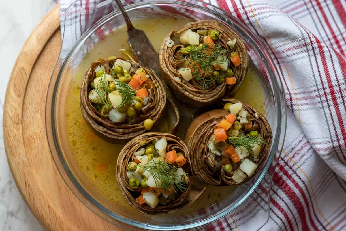 cooked Zeytinyagli enginar - stuffed artichokes are transferred on a dish
