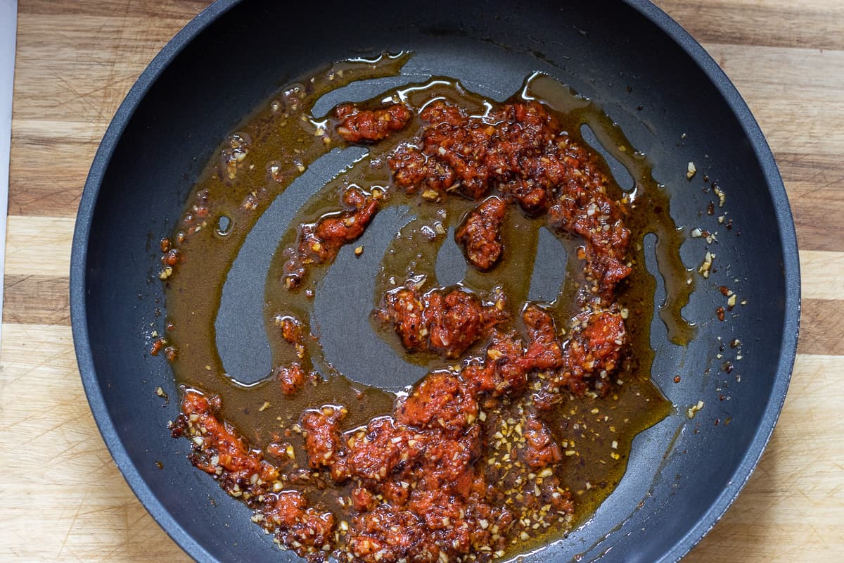 red pepper paste, black pepper and salt are added to the sautéed garlic