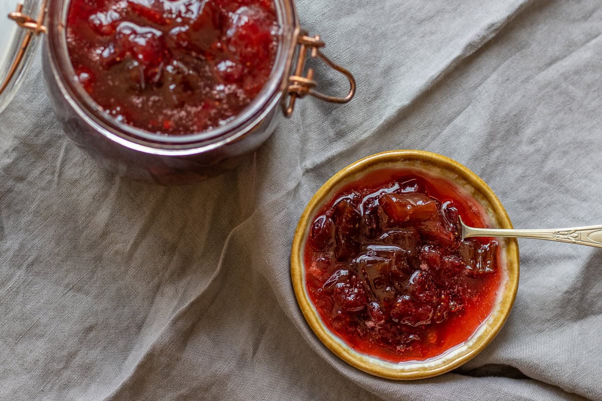 Strawberry and rhubarb jam in a jar and a small bowl.