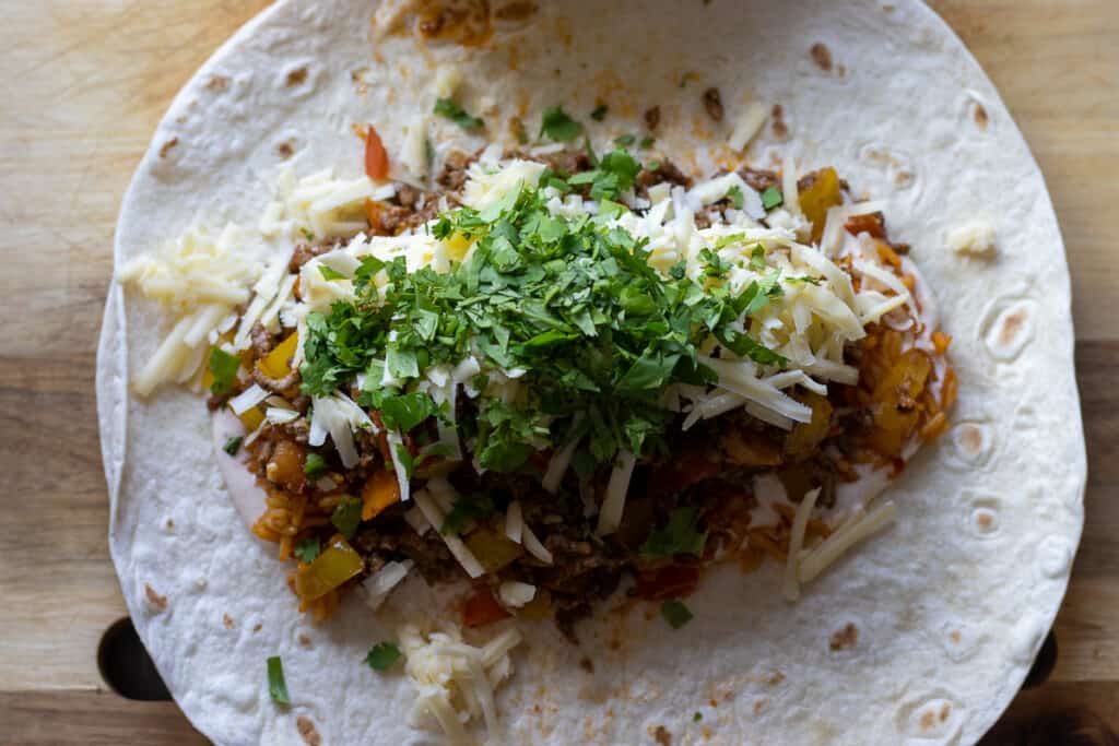 Shredded cheese and chopped coriander is added to the top of the filling.