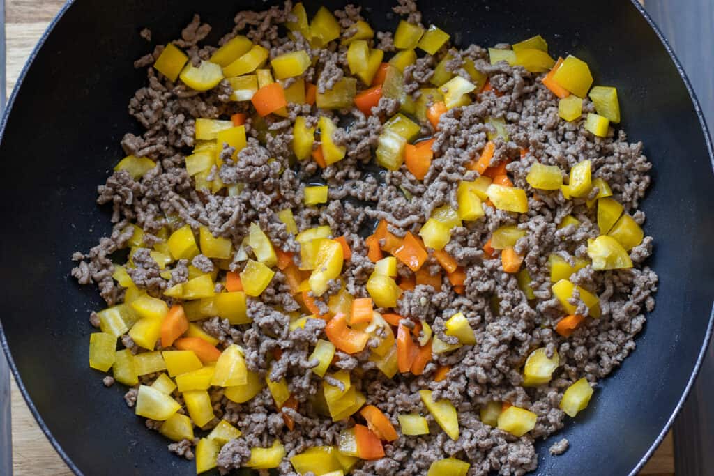 Sauteing the diced peppers with the browned beef.