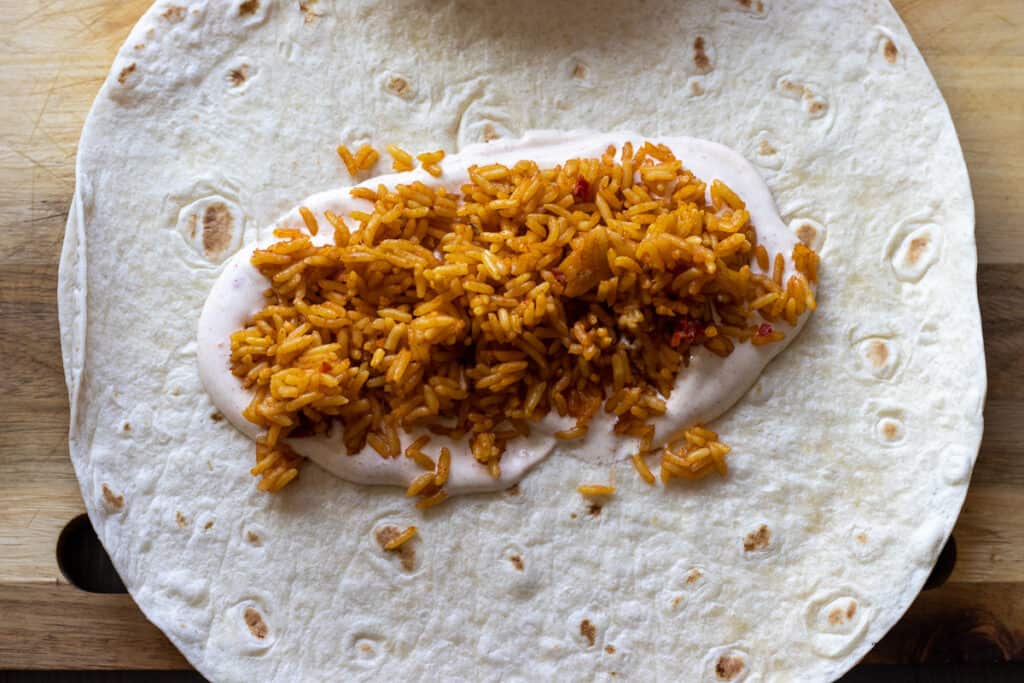 Mexican rice is placed on top of sour cream sauce.