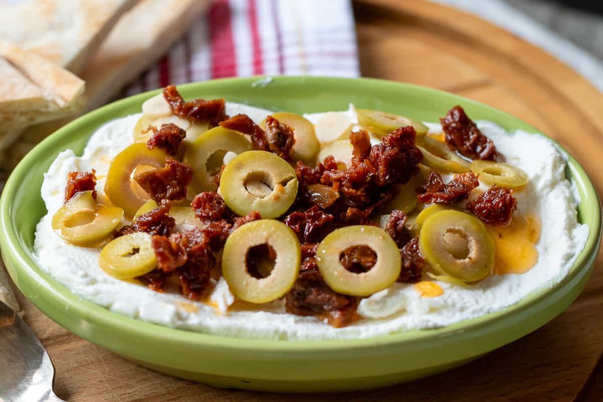 labneh is served with sliced olives and a drizzle of olive oil