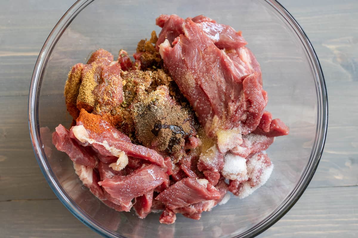 steak strips are placed in a bowl along with the marinade ingredients