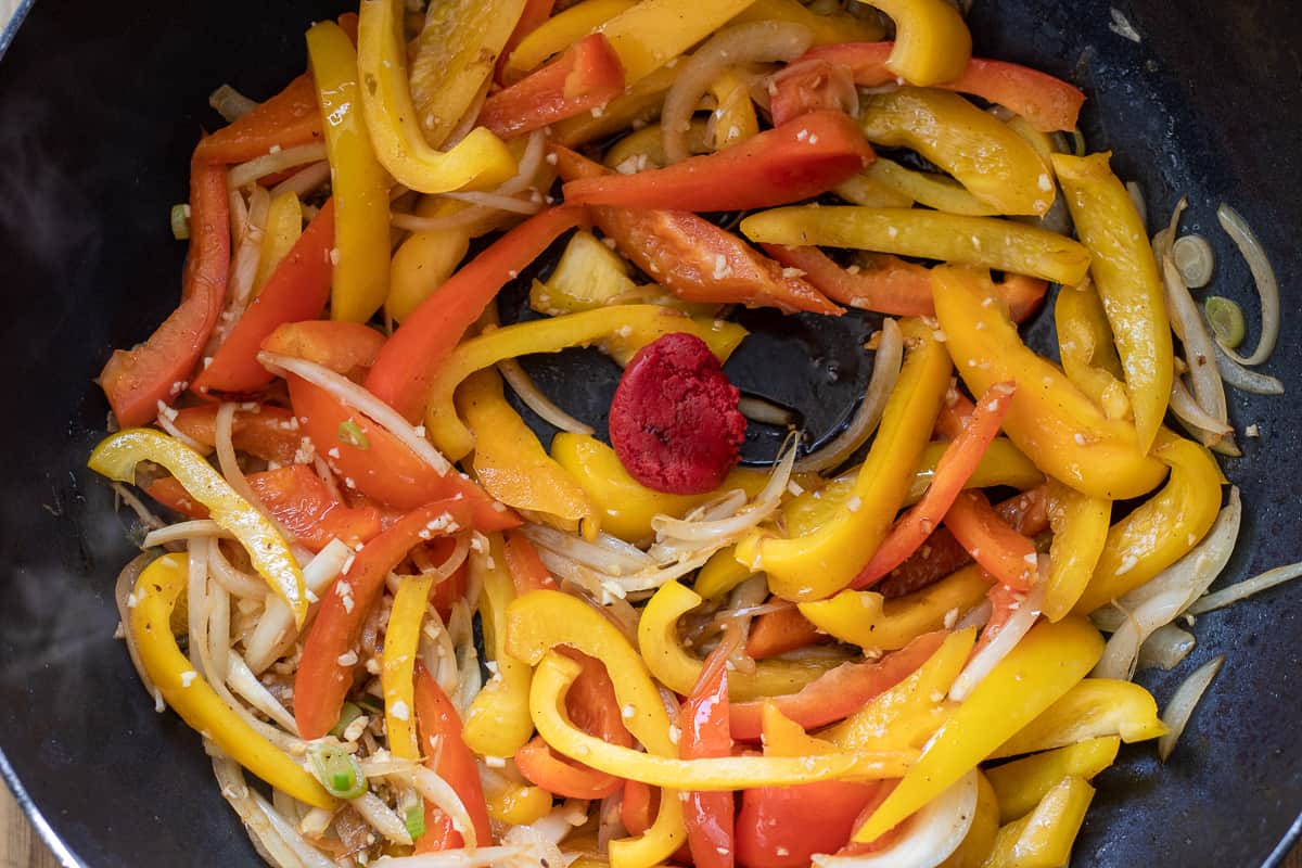 tomato paste, garlic, and ginger are added top the wok