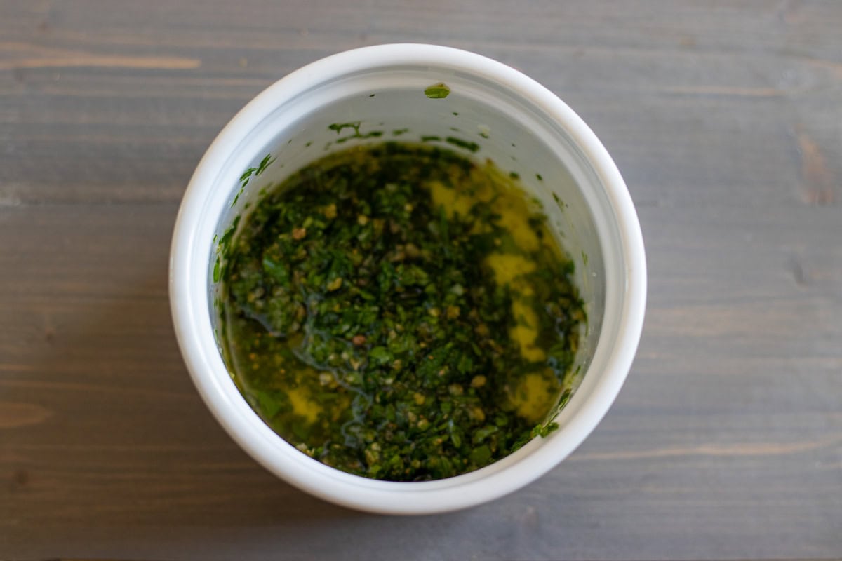 Herbs and seasoning are mixed with olive oil in a small bowl.
