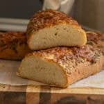 A bread loaf cut in half on a cutting board.