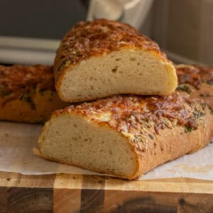 A bread loaf cut in half on a cutting board.