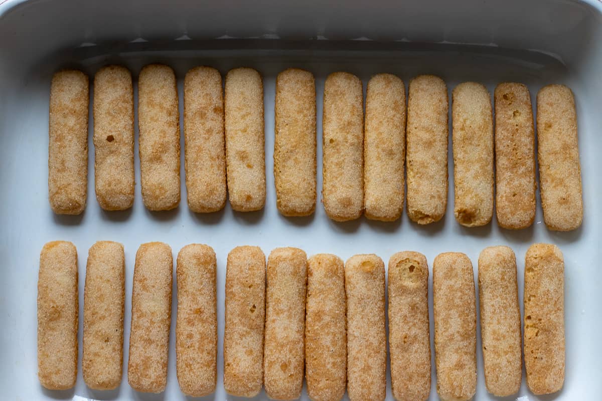half of the ladyfingers are arranged to the bottom of a baking dish