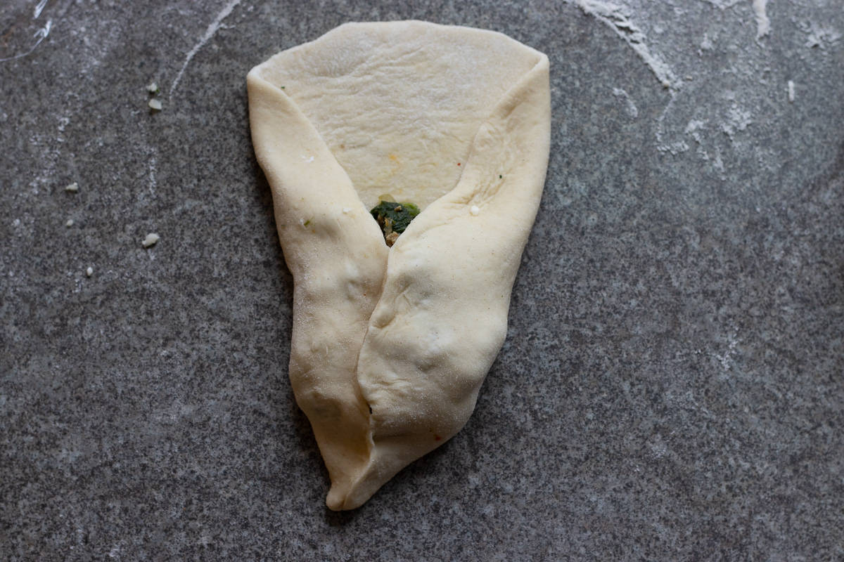 two sides of the dough brought together at the top, a bit to the side to create a point like a triangle.