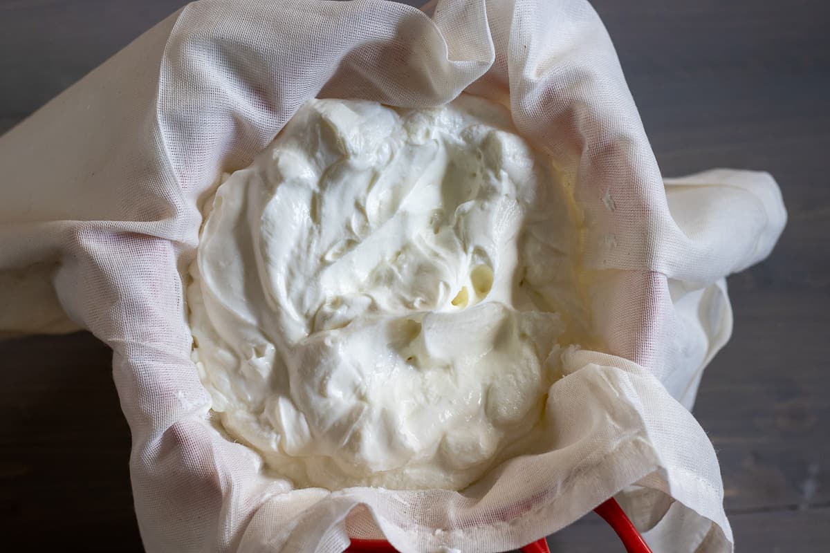 yogurt is placed in a cheesecloth over a sieve