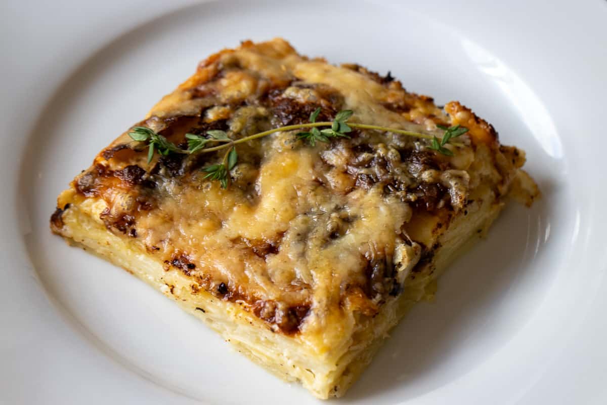 a portion of dauphinoise potatoes garnished with a sprig of thyme