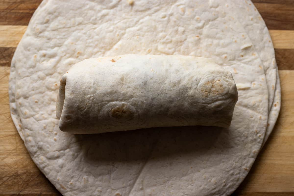 the sides of the tortilla are folded and wrapped into a burrito