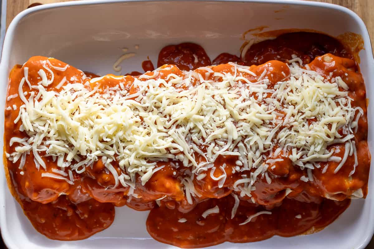 red sauce and shredded cheese are added to wet burritos
