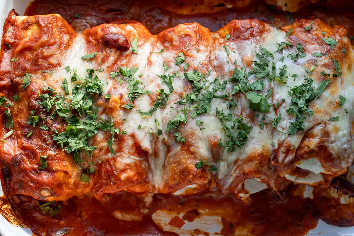 wet burritos with ground beef are garnished with coriander