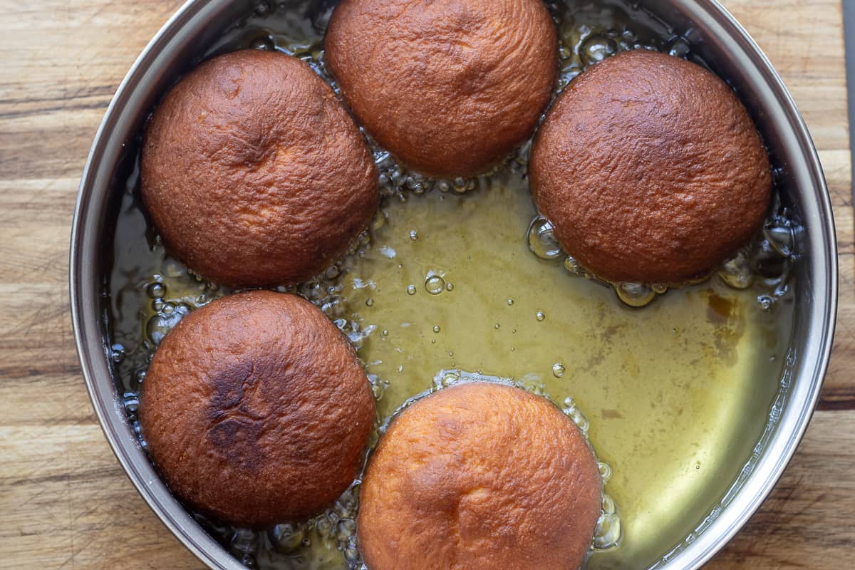 frying the doughnuts in a pan filled with hot oil