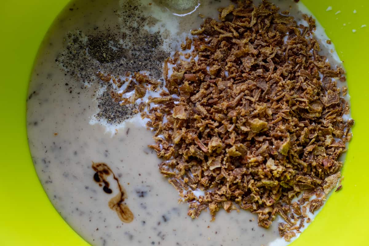 milk, mushroom soup, soy sauce, seasoning, and half of fried onions are mixed in a bowl