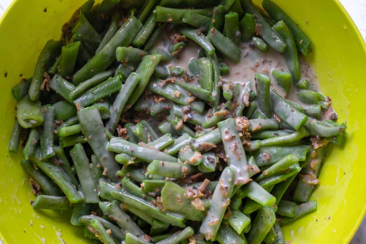 blanched green beans are mixed with milk mixture in the bowl