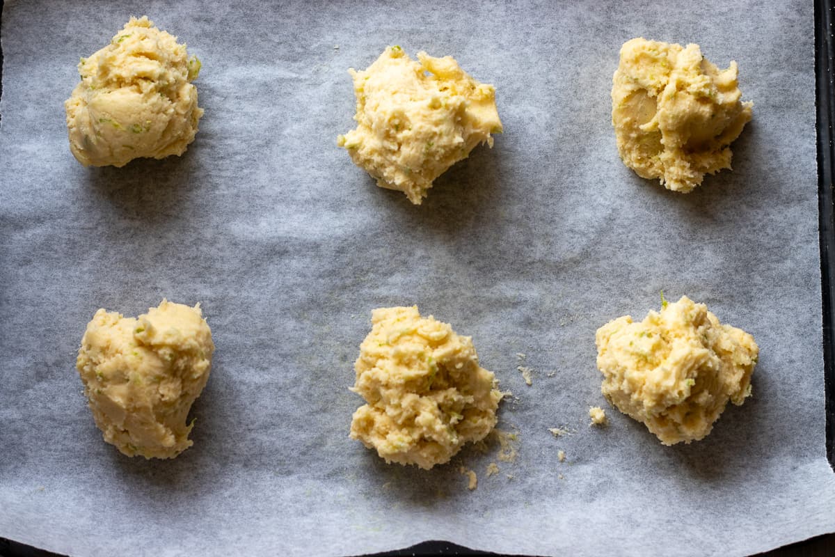 6 cookie dough balls are placed on a baking paper lined sheet