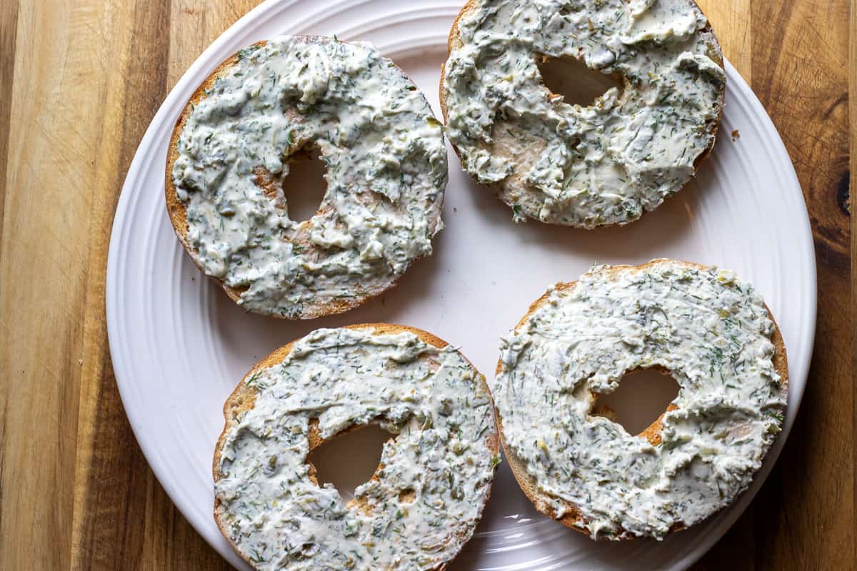 a generous amount of cream cheese is spread on toasted bagels