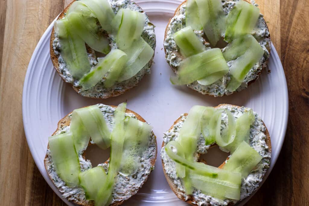 cucumber slices are placed on top of the bagels