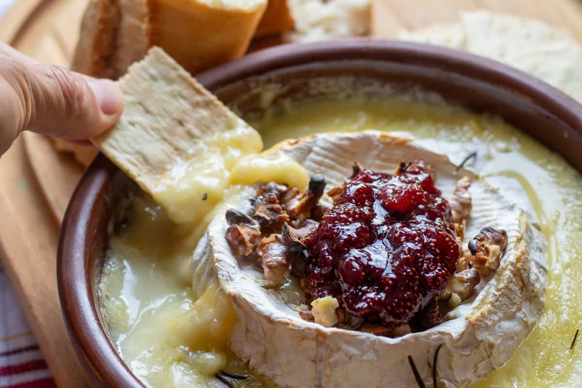dipping cheese biscuit into melted baked brie cheese