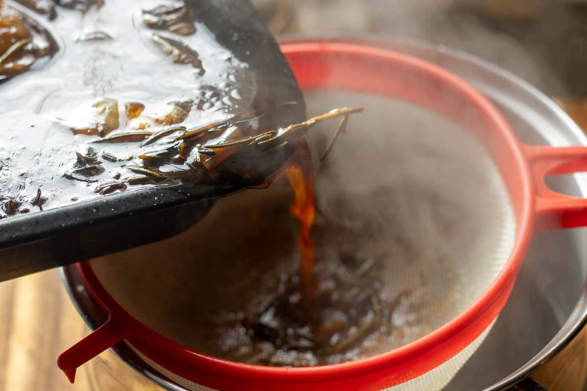 Straining the beef stock through a sieve.