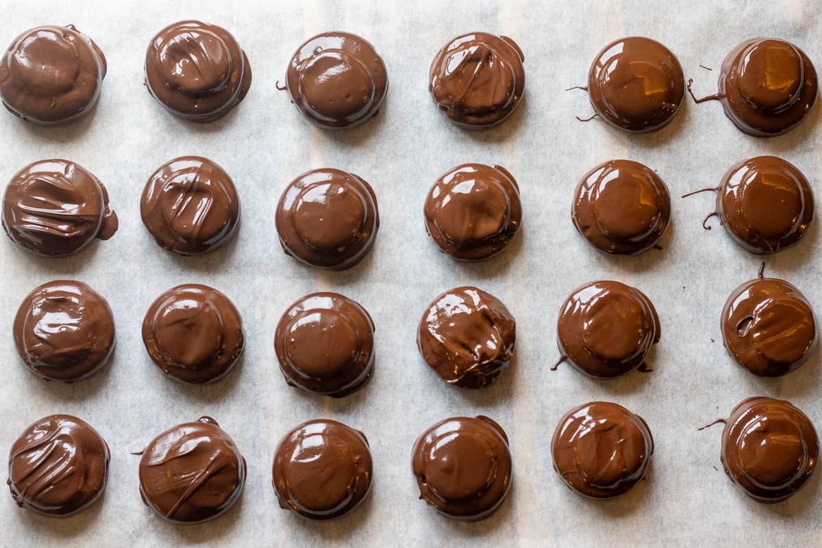 Oreos are dipped in chocolate and placed on a baking sheet.