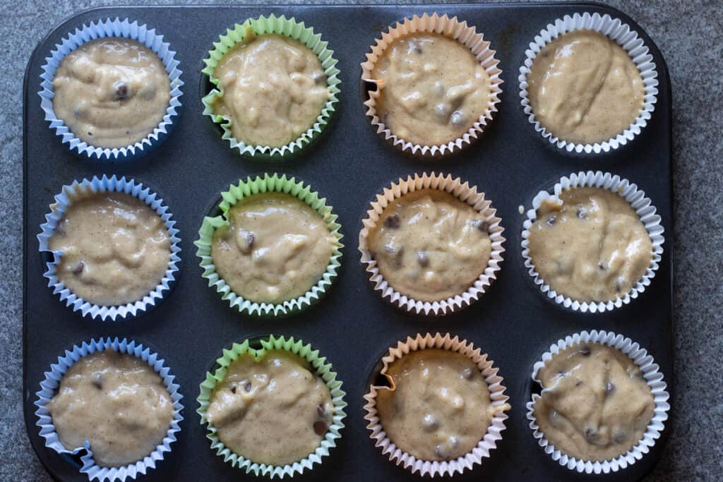 12 muffin cases are filled with banana pumpkin muffin batter.