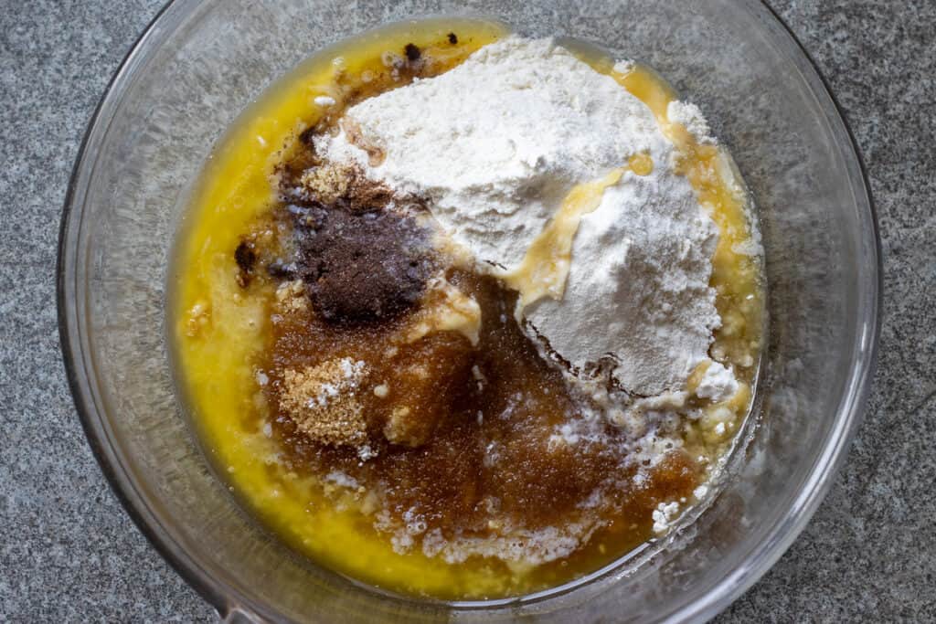 Flour, melted butter, cinnamon, walnuts, and sugar are placed in a glass bowl for making streusel.