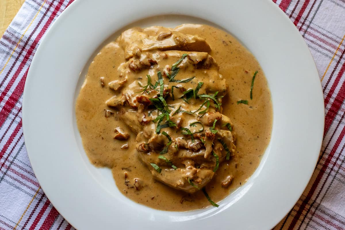 marry me chicken dish served on a white plate, garnished with basil leaves