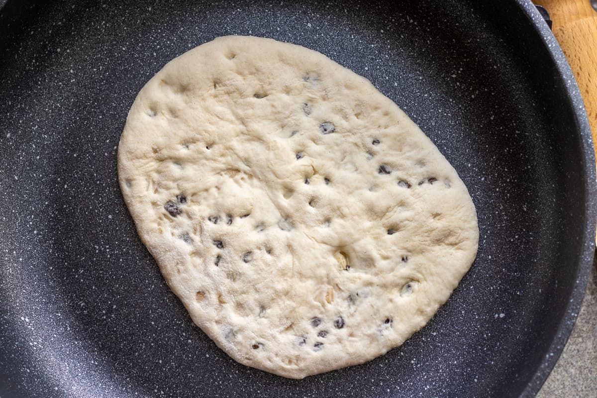 cooking a piece of peshwari naan in a hot pan