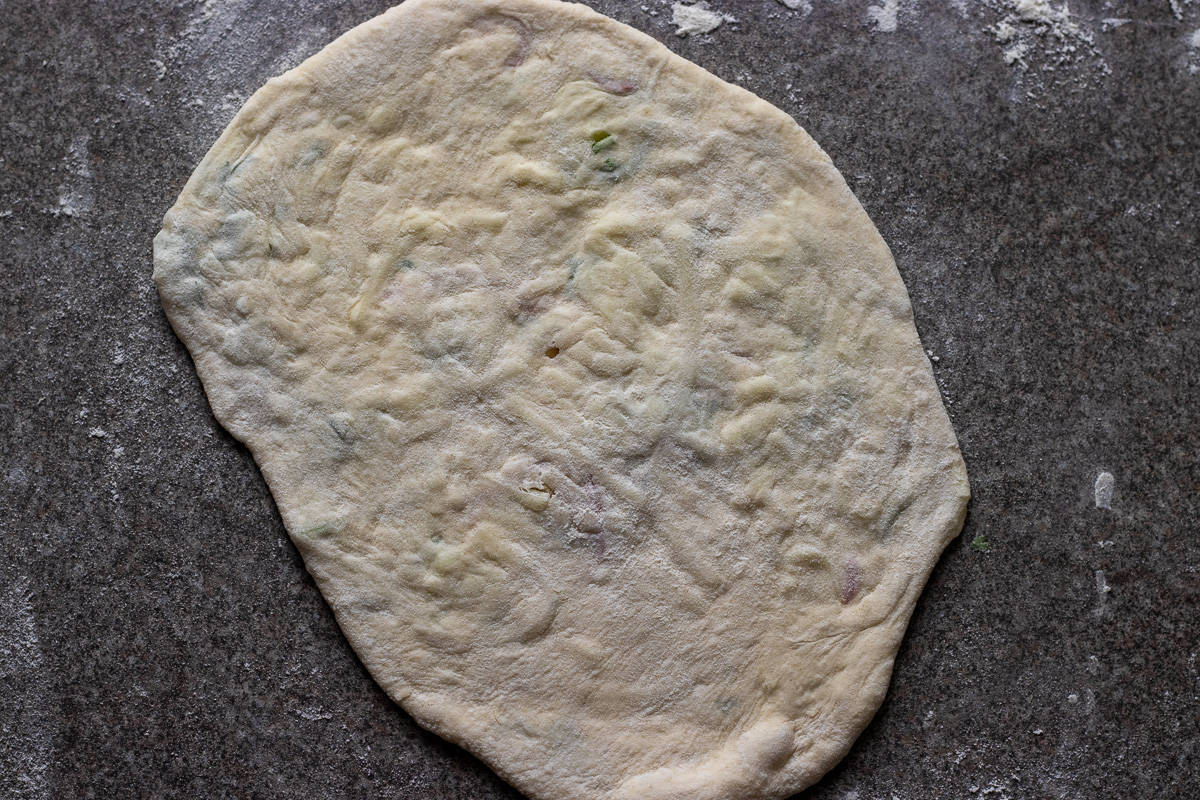 The dough ball is rolled out into a tear shape naan bread.