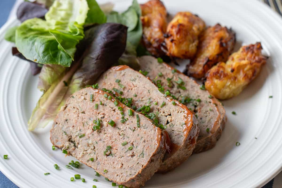 3 slices of meatloaves served with tater tots and salad
