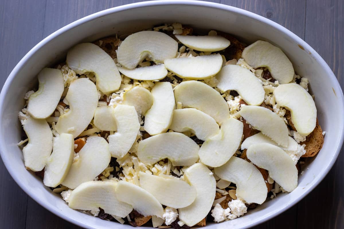 apples, raisins, and cheese are layered over soaked bread pieces