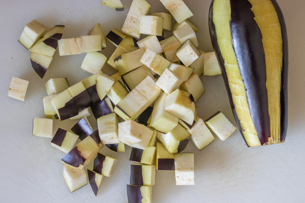eggplants are cut into small cubes for roasting