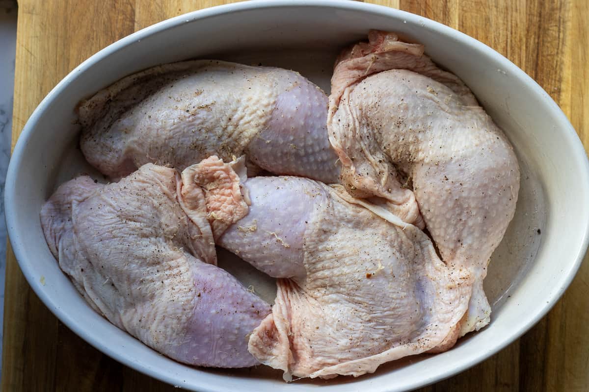 seasoned chicken leg quarters are placed in a baking dish