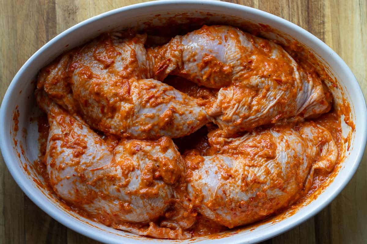 4 pieces of marinated chicken leg quarters in a baking dish