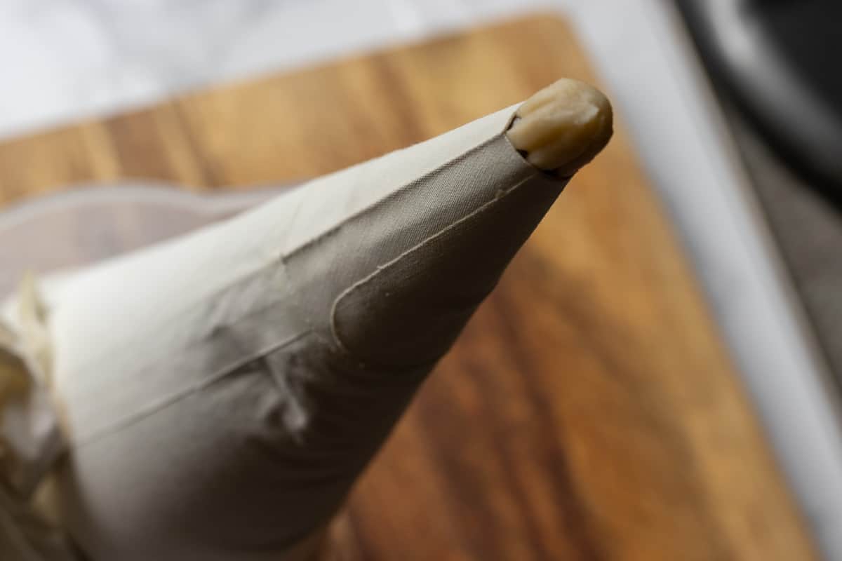 tulumba dough is transferred to a piping bag with a star nozzle