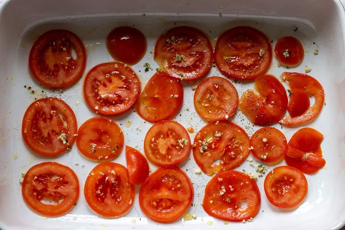 sliced tomatoes arranged on bottom of baking dish