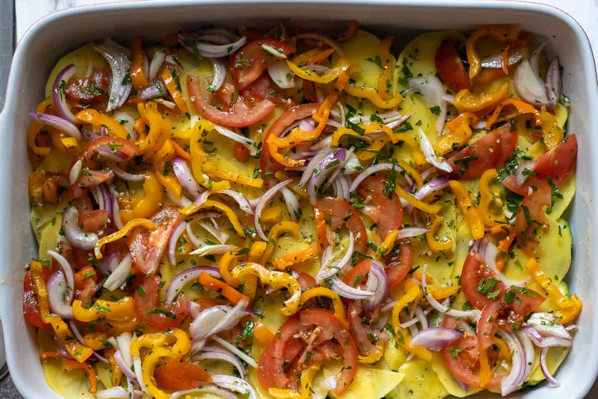sliced peppers and red onions sprinkled over potatoes