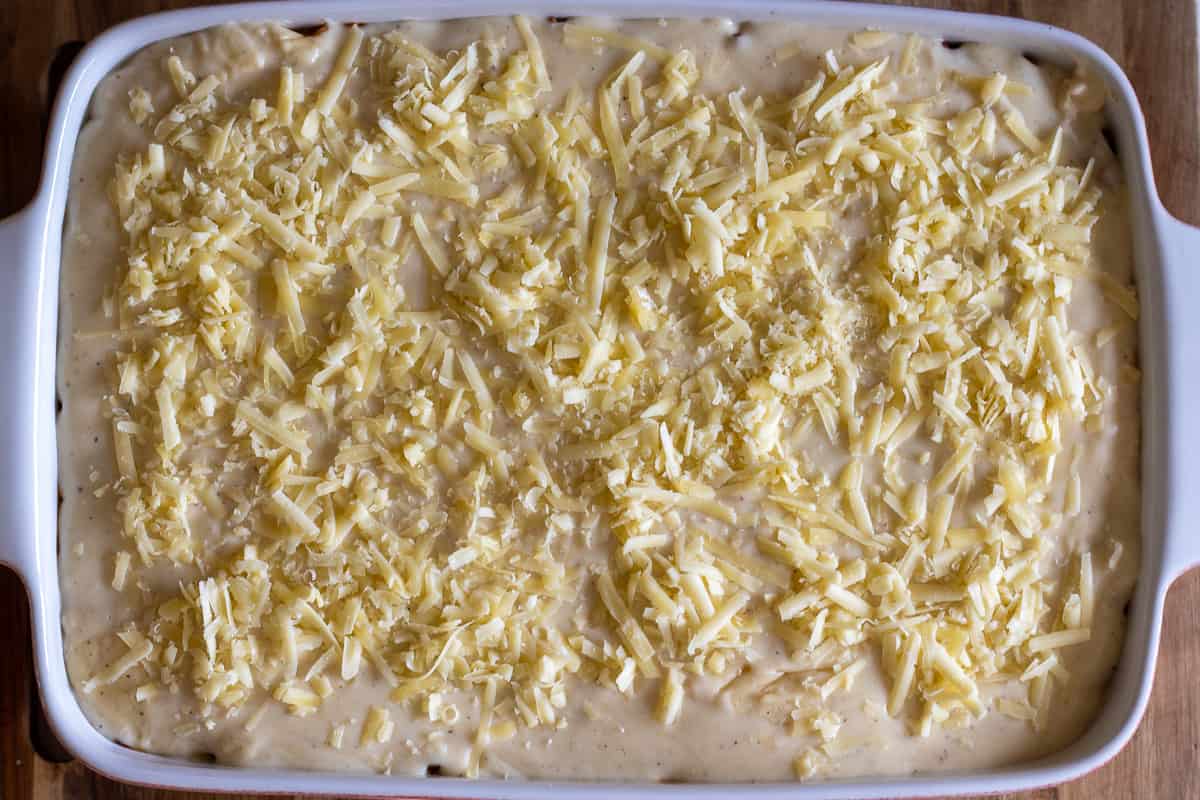 bechamel sauce is poured over the meat sauce and sprinkled with parmesan