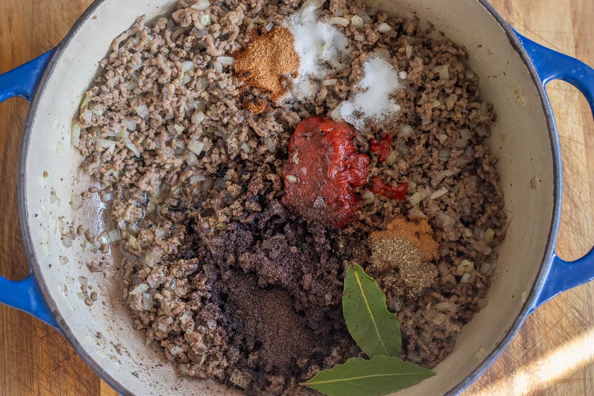 tomato paste, seasoning, bay leaves, and stock cube is added to the pan