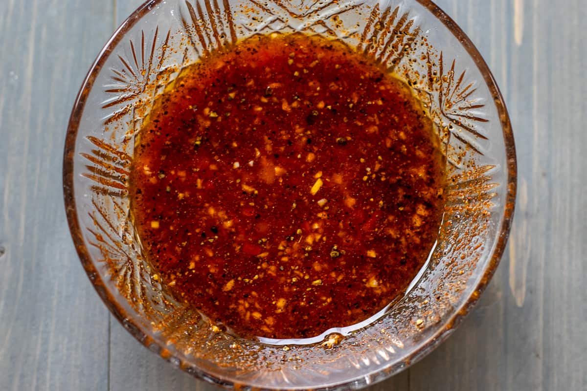 harissa paste, garlic, lime juice, olive oil, honey, and spices are placed in a bowl to make marinade for chicken harissa