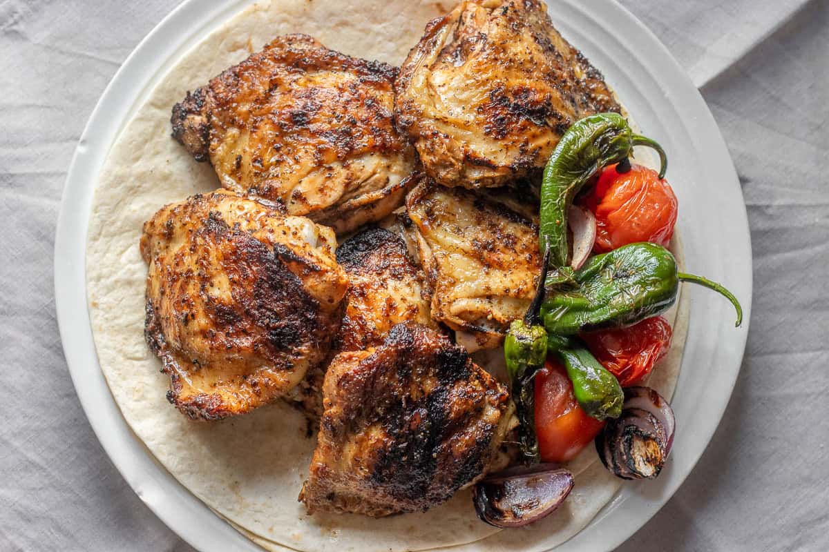6 pieces of chicken thighs grilled on bbq served with grilled
veggies