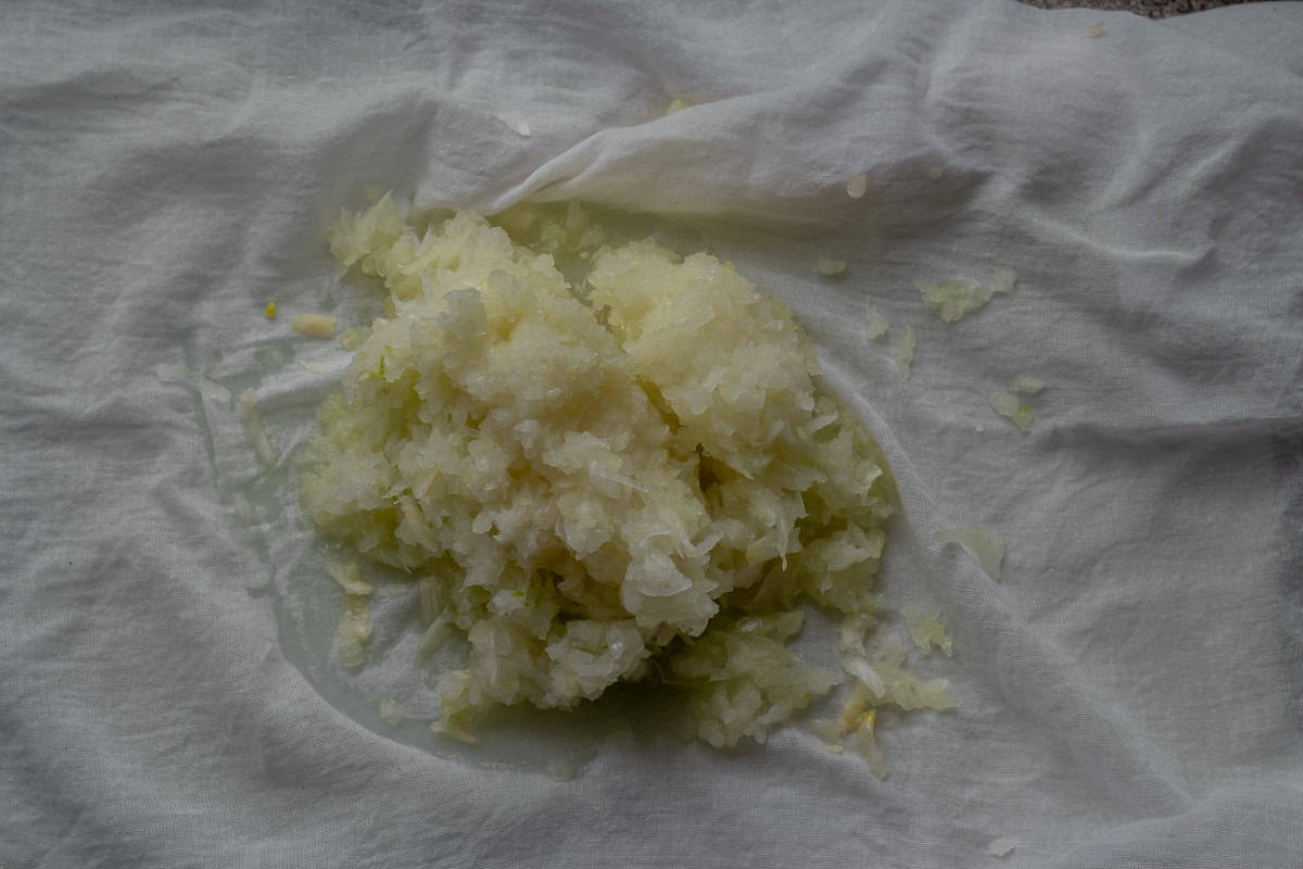 Grated onions are placed on a muslin cloth to squeeze the juice out of it.
