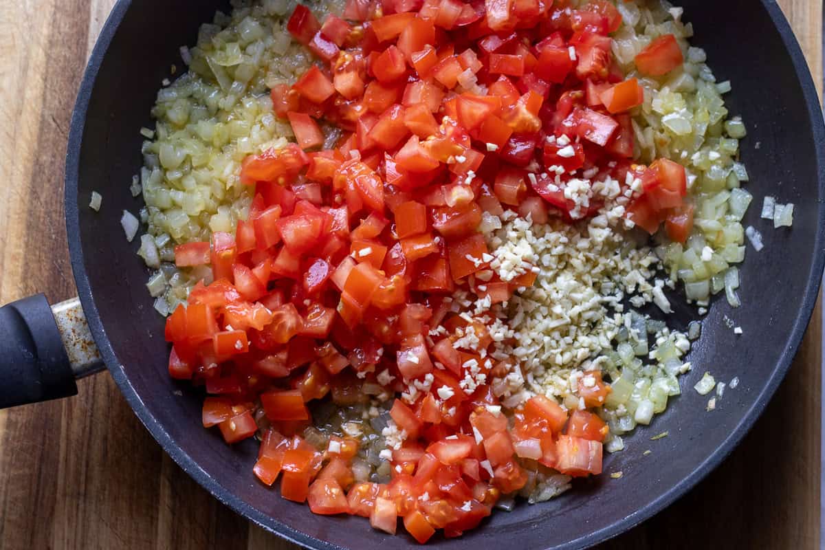 tomatoes and garlic are added to sautéed onions