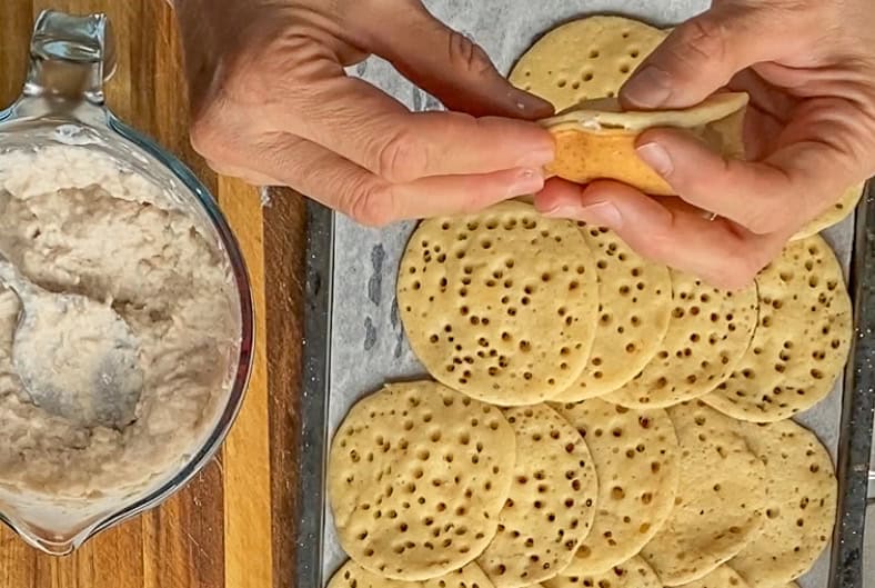 folding a piece of cheese filled pancake to form a Qatayef